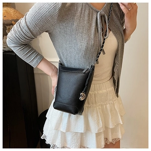 Détail du sac seau noir en cuir grainé avec chaîne argentée et breloque en cœur