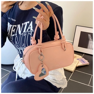 Détail du sac à main rose en cuir avec poignées nouées et breloque miroir en forme de cœur