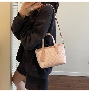 Sac fourre-tout rose à monogramme avec bandoulière et doubles poignées sur un mannequin