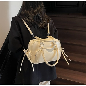 Detail of cream lychee texture leather Boston bag with round handles and tassel