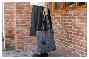 Detail view of large denim tote bag featuring vintage acid wash finish and metal buckle pocket