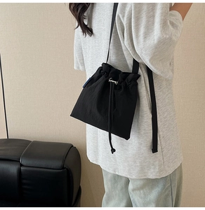 Détail du sac seau noir en nylon avec cordon de serrage et bandoulière réglable