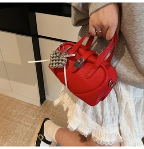 Détail du mini sac rouge en cuir grainé avec fermoir argenté et breloque ruban