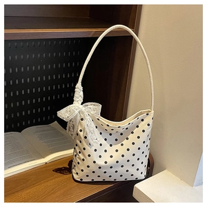 Dettaglio della borsa a pois bianchi con fiocco di pizzo su uno scaffale in legno