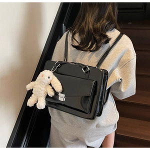 Détail d'un sac à dos en cuir verni noir avec finition brillante et breloque lapin en peluche