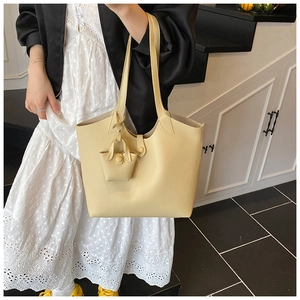 Close-up of light yellow lychee grain leather tote bag with matching mini charm pouch