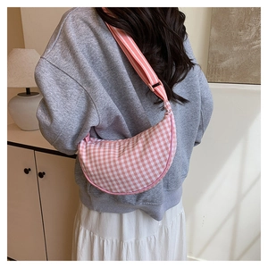 Pink plaid crescent crossbody bag with adjustable strap shown on model in casual style