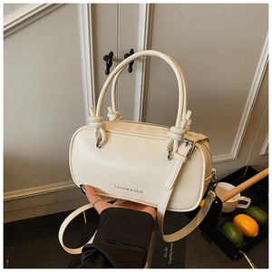 Gros plan d'un sac à main cylindrique blanc crème élégant avec texture de cuir fin