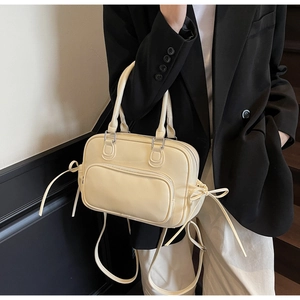 Detail of cream Boston bag featuring side bow accents and premium PU leather texture