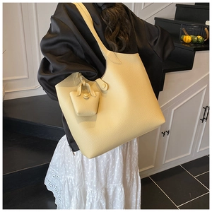 Close-up of pale yellow tote bag with lychee texture and matching mini bag charm