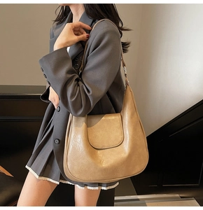 Detail shot of vintage beige hobo tote bag texture on female model in grey blazer