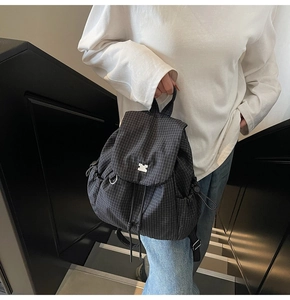Dettaglio dello zaino nero a scacchi con logo argento e trama in nylon leggero