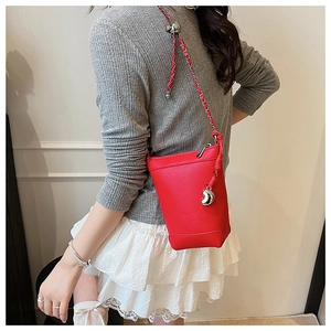 Gros plan d'un sac seau en cuir rouge avec bandoulière en chaîne et pendentif argenté