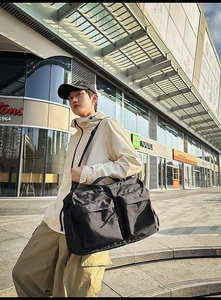 Grand sac de voyage noir en nylon avec poches tactiques porté dans une scène de rue