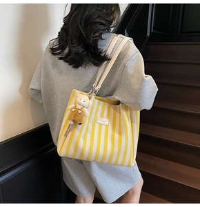 Détail du sac cabas en toile à rayures jaunes avec bandoulières et porte-clés ours
