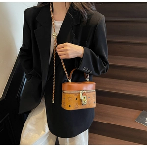 Brown vintage vanity box bag with gold chain strap shown on model in a stylish indoor setting