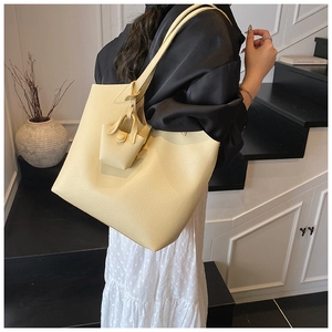 Close-up of large pale yellow leather tote bag with pebble grain and matching mini pouch