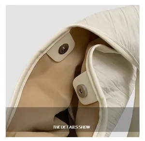 Détail du fermoir magnétique argenté et du tissu plissé texturé d'un sac cabas blanc