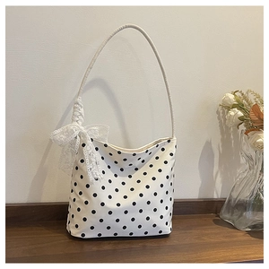 Dettaglio della borsa a tracolla bianca a pois con un grande fiocco in pizzo decorativo