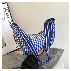 Detail of blue and white checkered crescent canvas bag with striped adjustable strap