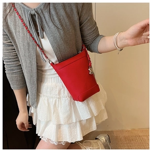 Détail du mini sac seau rouge en cuir grainé avec bandoulière chaîne et pendentif argent
