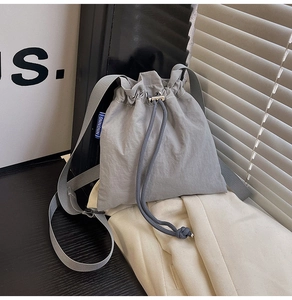 Détail du sac seau en nylon gris montrant le cordon et l'étiquette tissée NINGNING bleue
