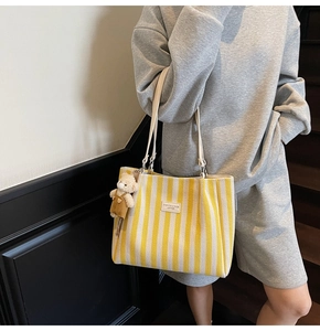 Détail du sac cabas en toile rayée avec écusson de mode et breloque ours mignon