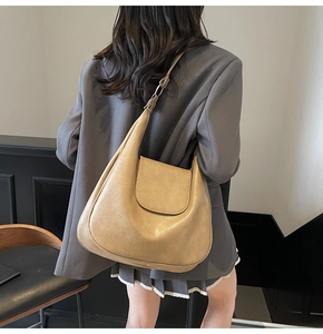 Close-up of beige leather crescent hobo bag with adjustable strap and textured finish