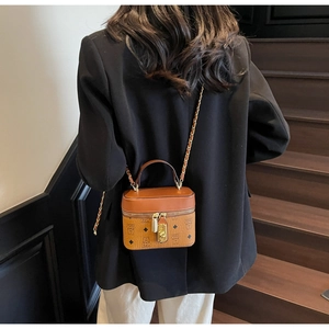 Rear view of model wearing a brown patterned crossbody bucket bag on a staircase