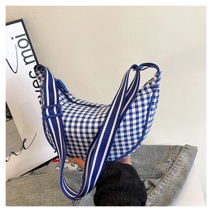 Detail of blue and white checkered crescent bag with wide striped shoulder strap