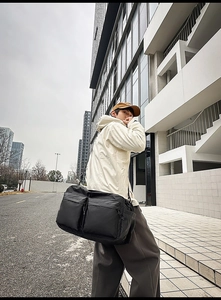 Détail du grand sac de voyage en nylon noir avec poches utilitaires et bandoulière large