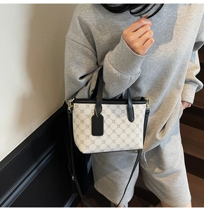 Détail du mini sac cabas avec motif monogramme vintage et étiquette en cuir noir