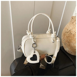 Détail du sac à main blanc en similicuir avec poignée nouée et breloque miroir cœur