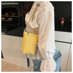 Détail du sac seau jaune en cuir grainé avec bandoulière en chaîne argentée