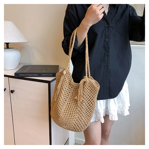 Detail of beige hollow woven tote bag with fringe tassel in a cozy minimalist interior