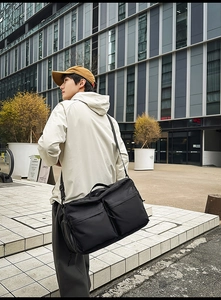 Détail du sac de voyage en nylon noir avec plusieurs fermetures éclair et bandoulière réglable