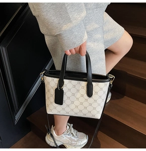 Détail d'un sac seau en toile avec motif quadrillé et boucles dorées sur escalier