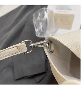 Detailed macro view of cream lychee leather texture and shiny silver metal hardware hook
