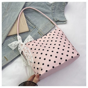 Dettaglio della borsa rosa a pois con fiocco in pizzo bianco su uno sfondo lifestyle