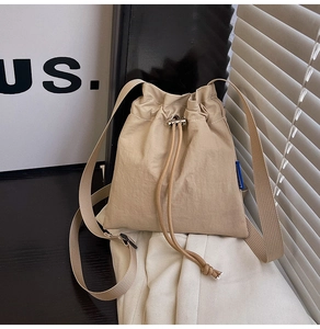 Détail d'un sac seau beige à cordon avec texture en nylon plissé et bandoulière réglable