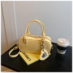 Détail du sac oreiller jaune clair avec poignées nouées et miroir cœur sur table en bois