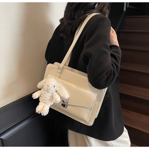 Détail d'un sac cabas en similicuir beige avec boucle argentée et charm lapin en peluche