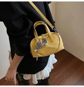 Détail d'un sac Boston jaune vif en cuir litchi avec serrure argentée et breloque perle