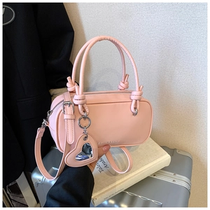 Détail du sac polochon rose avec poignée nouée et charm miroir en forme de cœur