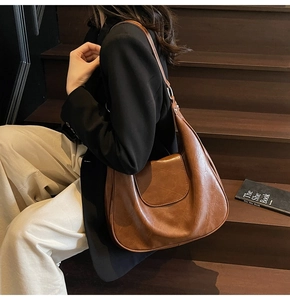 Brown vintage hobo bag on model, featuring crescent shape and smooth faux leather texture