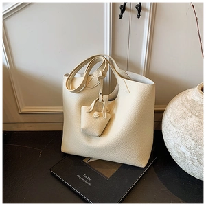 Close-up of off-white lychee grain leather tote bag with matching mini bag charm