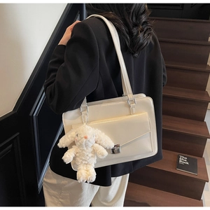 Détail du sac bandoulière en similicuir crème avec boucle en métal et breloque lapin