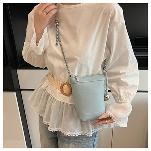 Détail du mini sac seau en cuir bleu clair avec bandoulière chaîne et pendentif en métal