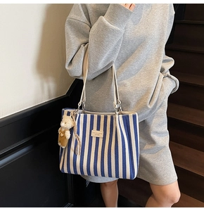 Détail du cabas en toile à rayures bleues et blanches avec étiquette et ours peluche