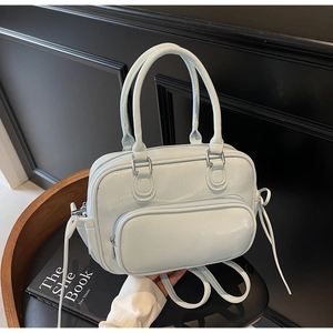 Close-up of light blue patent leather Boston bag with silver hardware and front zipper pocket